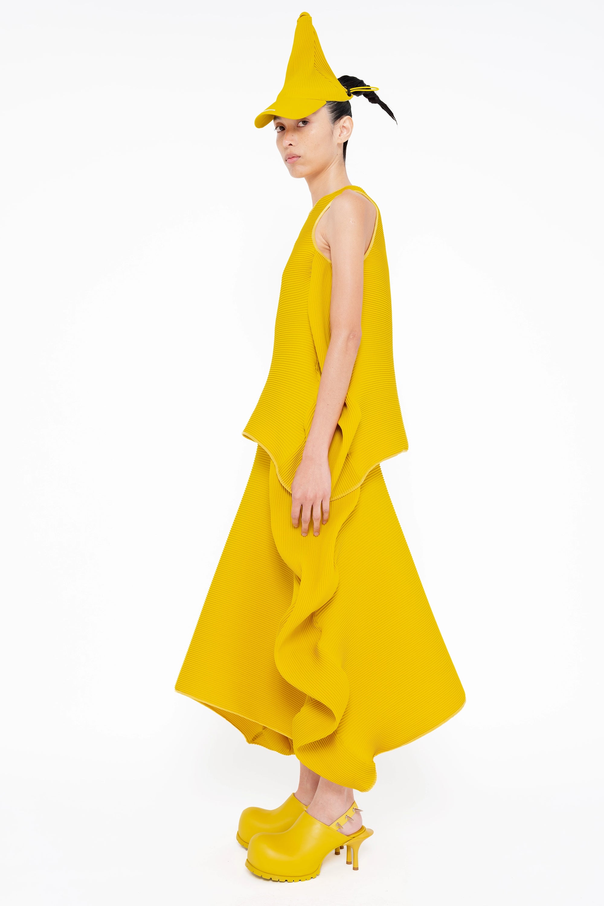 female-wearing-yellow-pleated-top-with-ruffles-and-yellow-long-pleated-skirt-with-ruffles-on-white-background-full-body-side