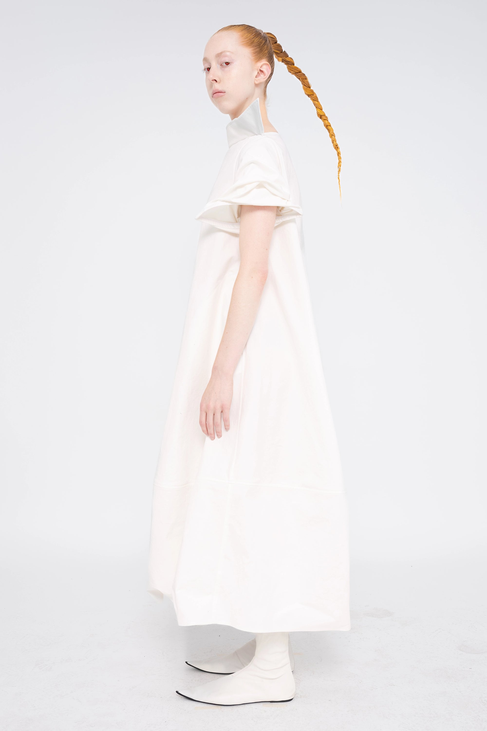 female-wearing-white-maxi-dress-with-stand-up-collar-and-short-pointy-sleeves-on-white-background-full-body-side