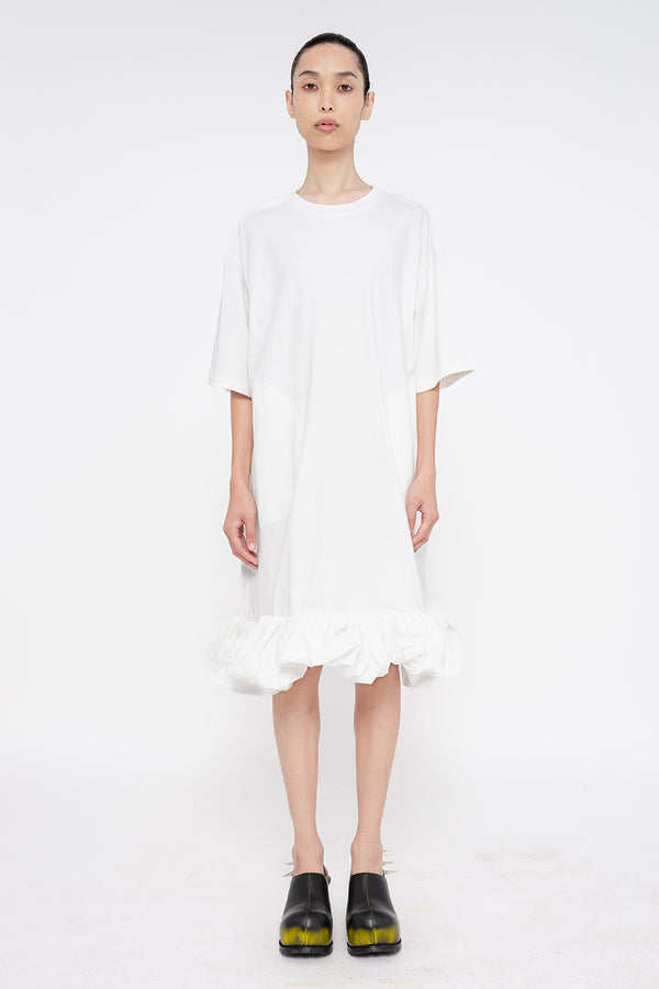 PERSON-WEARING-WHITE-TEE-DRESS-WITH-PUFFED-BOTTOM-EDGE-WITH-SPIKED-DOUBLE-HEEL-MULES-IN-PAINTED-BLACK-FRONT-VIEW