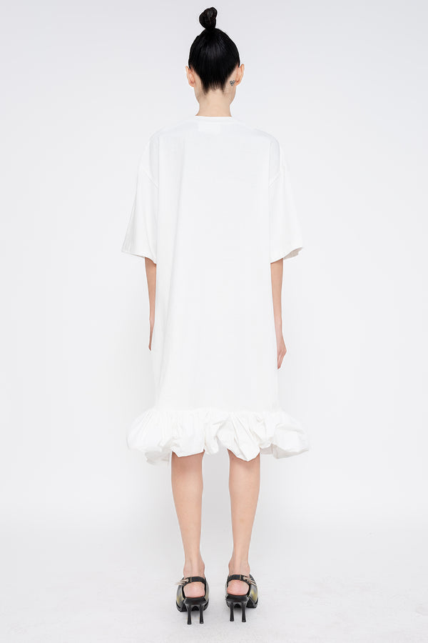 PERSON-WEARING-WHITE-TEE-DRESS-WITH-PUFFED-BOTTOM-EDGE-WITH-SPIKED-DOUBLE-HEEL-MULES-IN-PAINTED-BLACK-BACK-VIEW