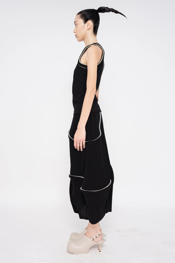 brunette-model-white-background-wearing-black-tank-top-with-foam-sleeve-and-collar-edge-detail-wearing-soft-skirt-with-foam-detail-with-off-white-double-heeled-spikey-mules-full-body-side