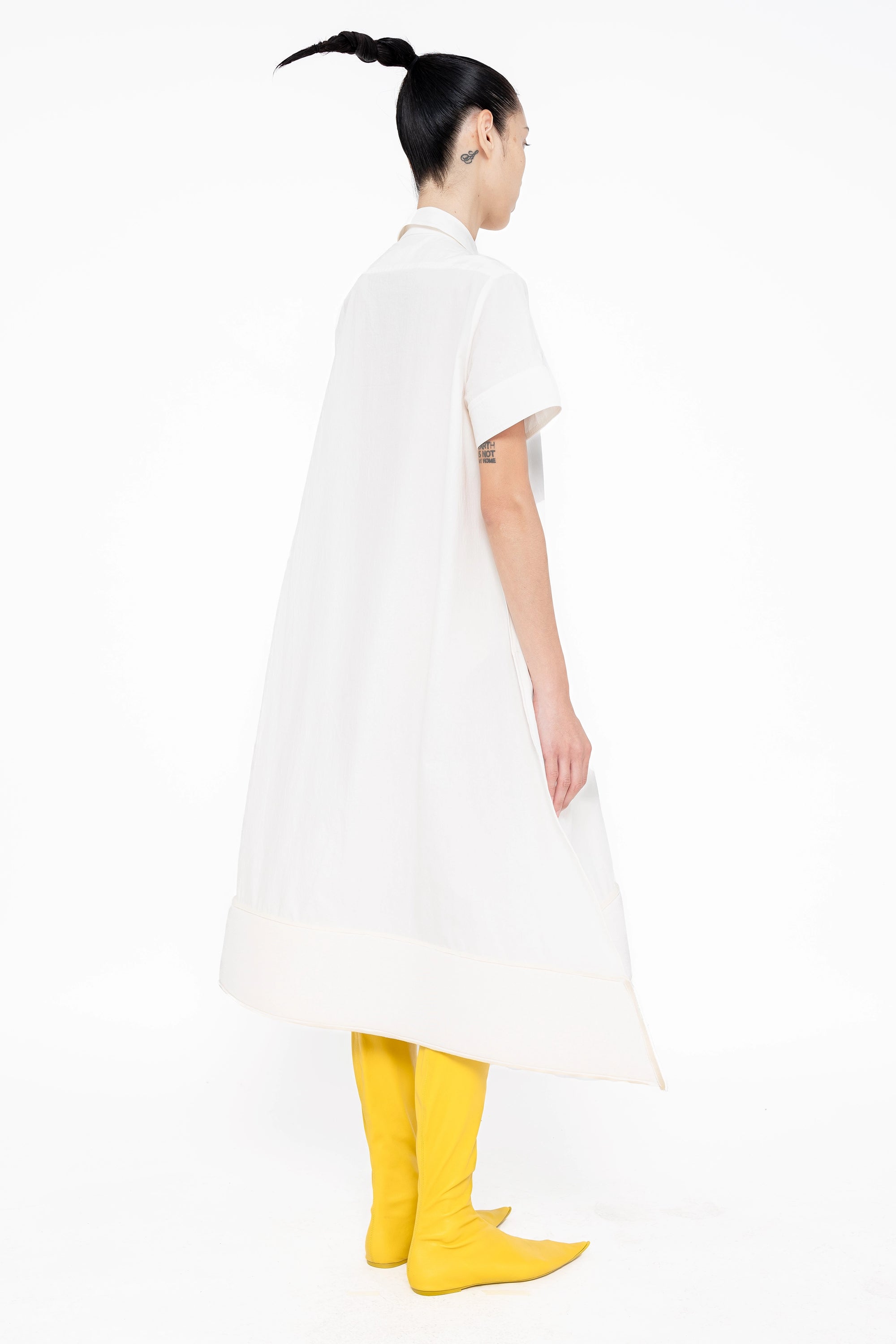 female-wearing-white-shirt-dress-with-pointy-hem-on-white-background-full-body-back-side