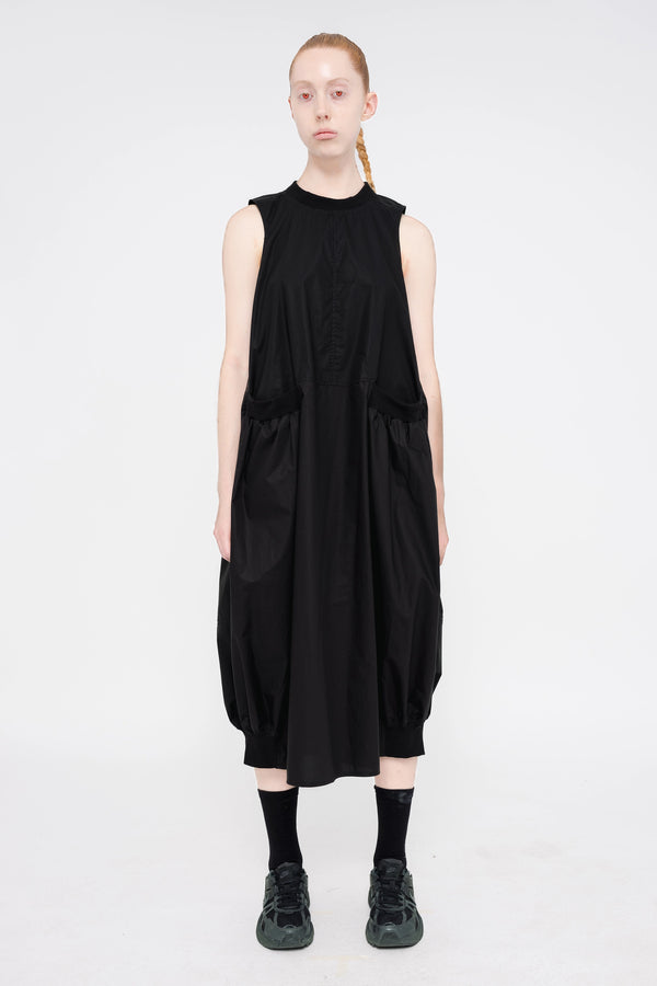 PERSON-WEARING-BLACK-SLEEVELESS-O-LINE-DRESS-WITH-FRONT-POCKETS-WITH-ATHLETIC-SNEAKERS-FRONT-VIEW