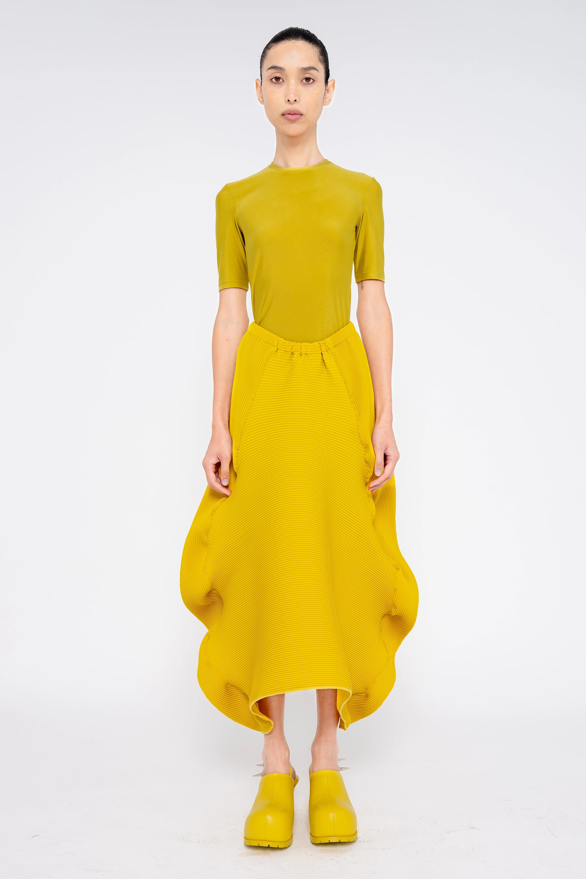 brunette-model-wearing-mustard-yellow-shirt-and-structured-ruffle-skirt-with-mustard-yellow-spikey-double-heeled-mules-full-body-front