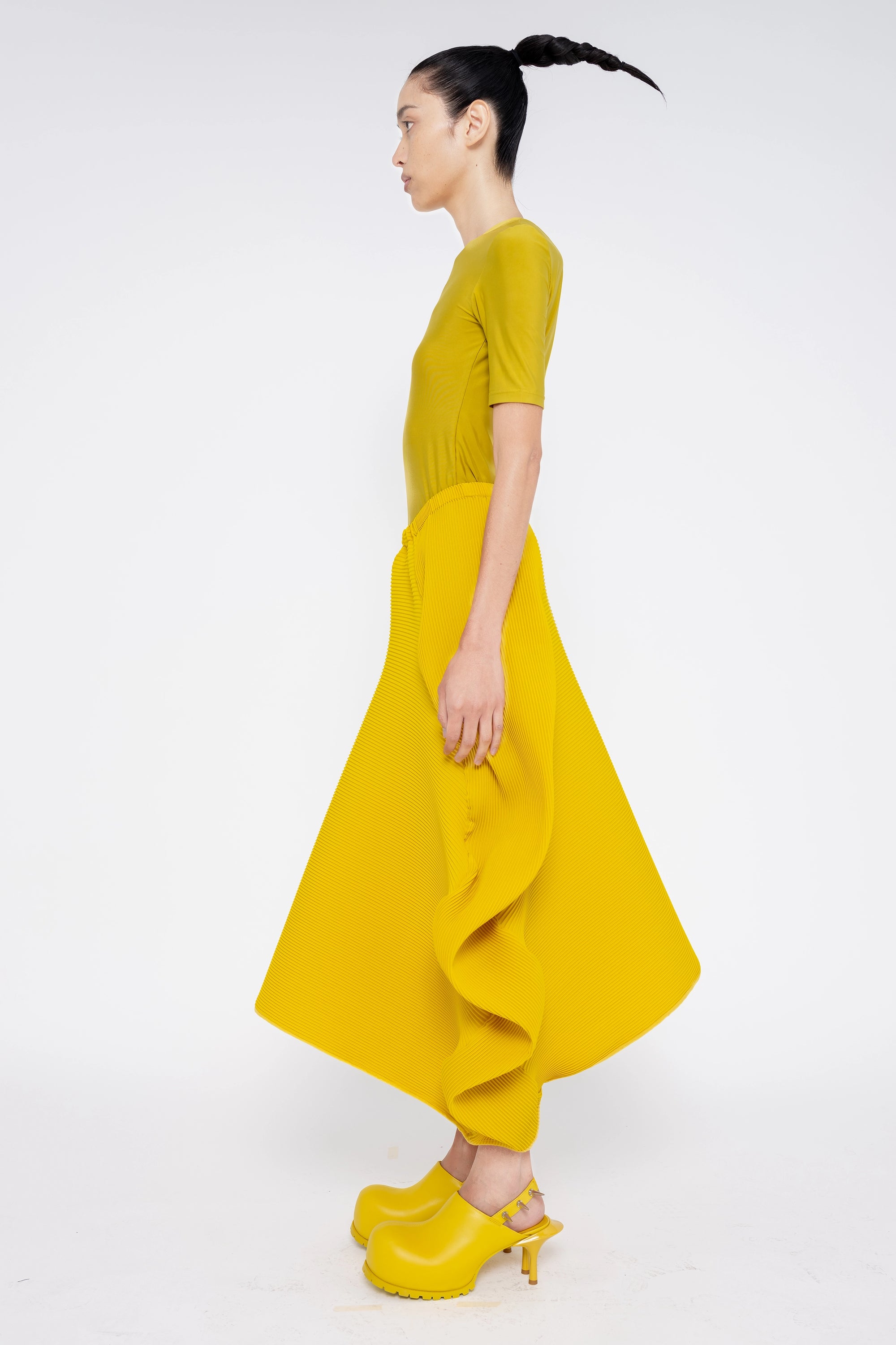 brunette-model-wearing-mustard-yellow-shirt-and-structured-ruffle-skirt-with-mustard-yellow-spikey-double-heeled-mules-full-body-side