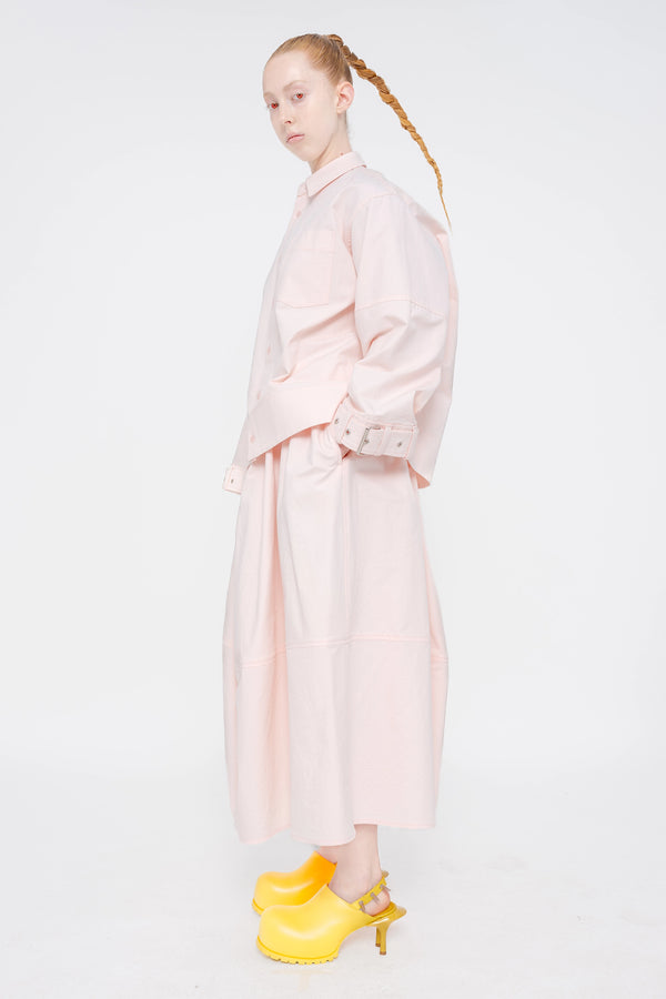 blonde-model-red-eyes-white-background-wearing-soft-pick-shirt-with-belted-sleeve-detail-and-soft-pink-volume-skirt-with-mustard-yellow-spikey-doubled-heeled-mules-full-body-side