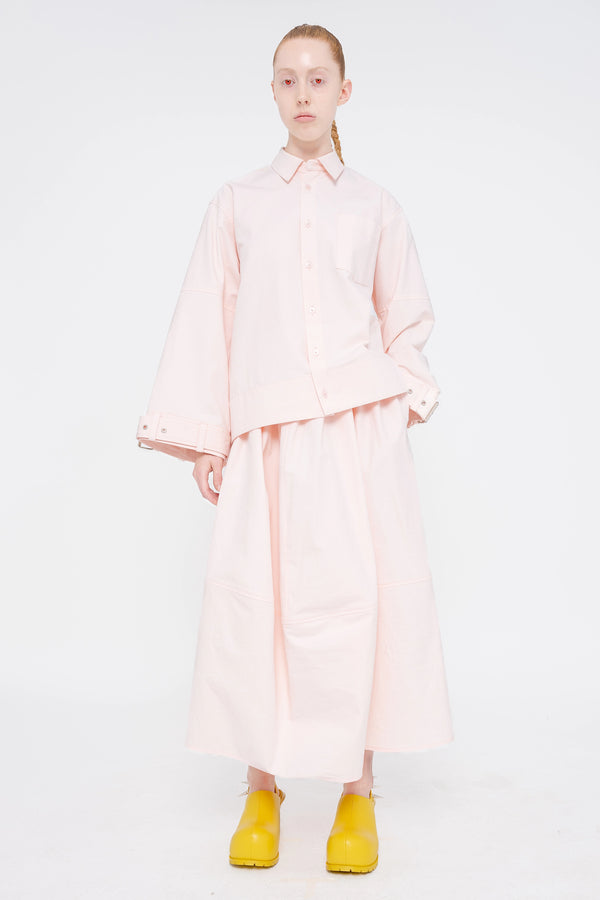 blonde-model-red-eyes-white-background-wearing-soft-pick-shirt-with-belted-sleeve-detail-and-soft-pink-volume-skirt-with-mustard-yellow-spikey-doubled-heeled-mules-full-body-front