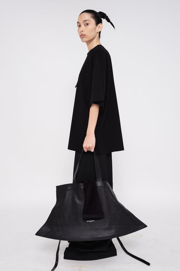 PERSON-WEARING-BLACK-SHIRT-WITH-BLACK-PANTS-AND-BLACK-SLOUCHY-POINTY-WEEKENDER-BAG-WITH-CROSSBODY-STRAP-SIDE-VIEW