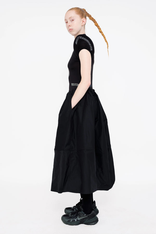 female-wearing-black-spongy-shoulder-top-and-black-maxi-volume-skirt-on-white-background-full-body-side