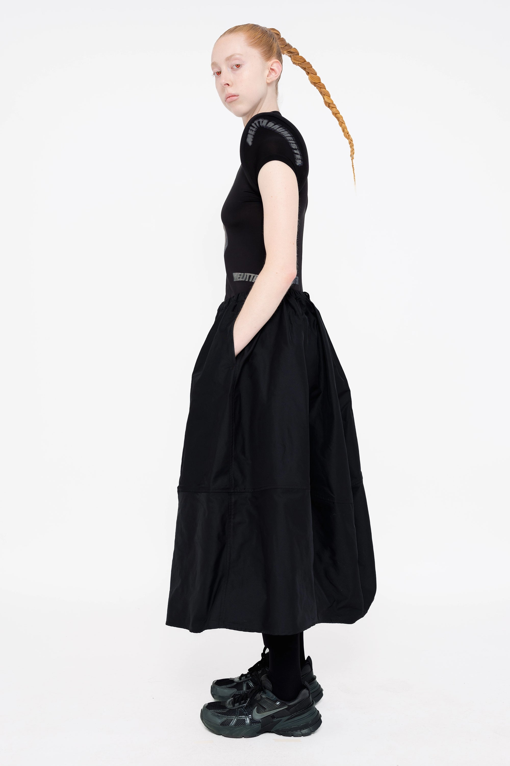 female-wearing-black-top-with-prominent-shoulders-and-white-0-screenprint-with-black-maxi-skirt-on-white-background-full-body-side