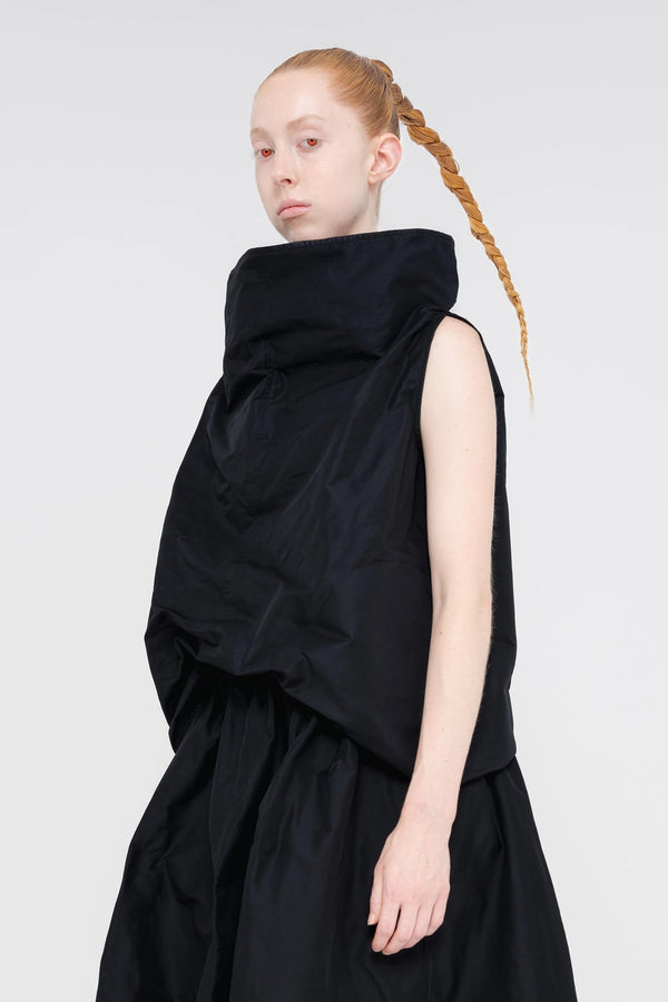 blonde-female-model-white-background-black-boatneck-top-and-skirt-red-eyes-quarter-view