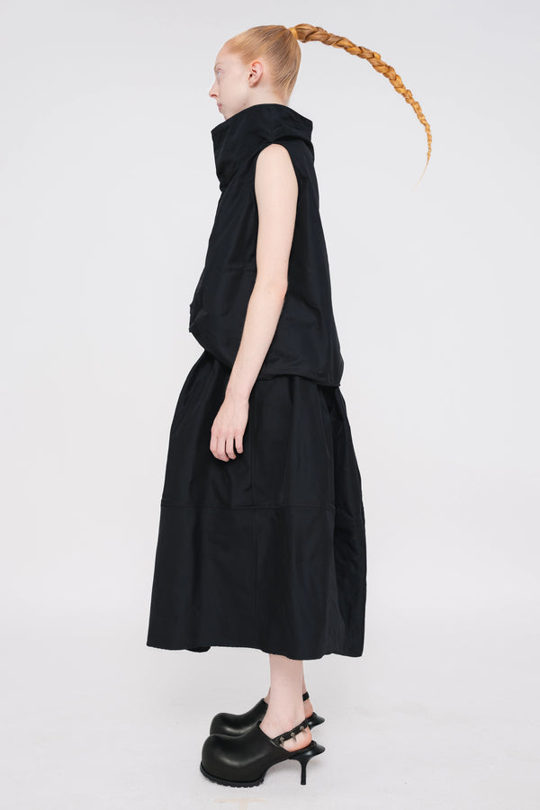 blonde-female-model-white-background-black-sleeveless-boatneck-top-and-skirt-and-black-spikey-doubled-heeled-mules-full-body-side