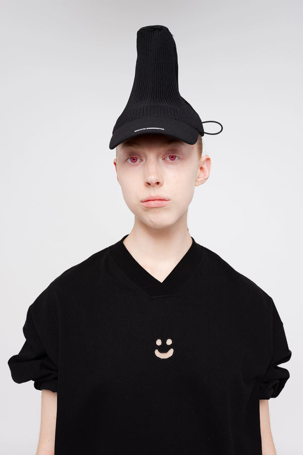 blonde-woman-white-background-black-shirt-black-pleated-cap-red-eyes
