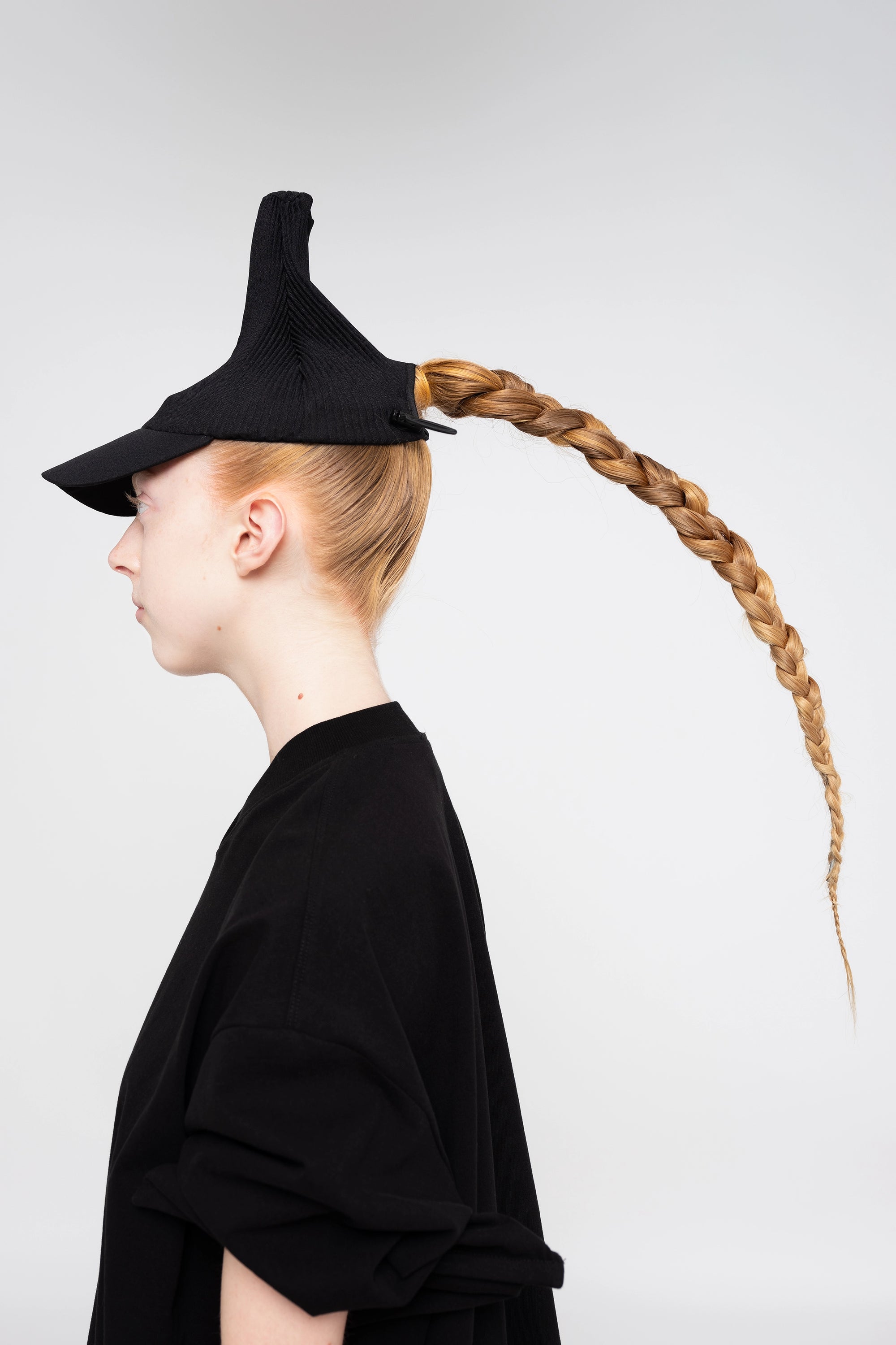 blonde-woman-white-background-black-shirt-black-pleated-cap