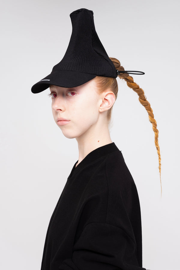 blonde-woman-white-background-black-shirt-black-pleated-cap-red-eyes