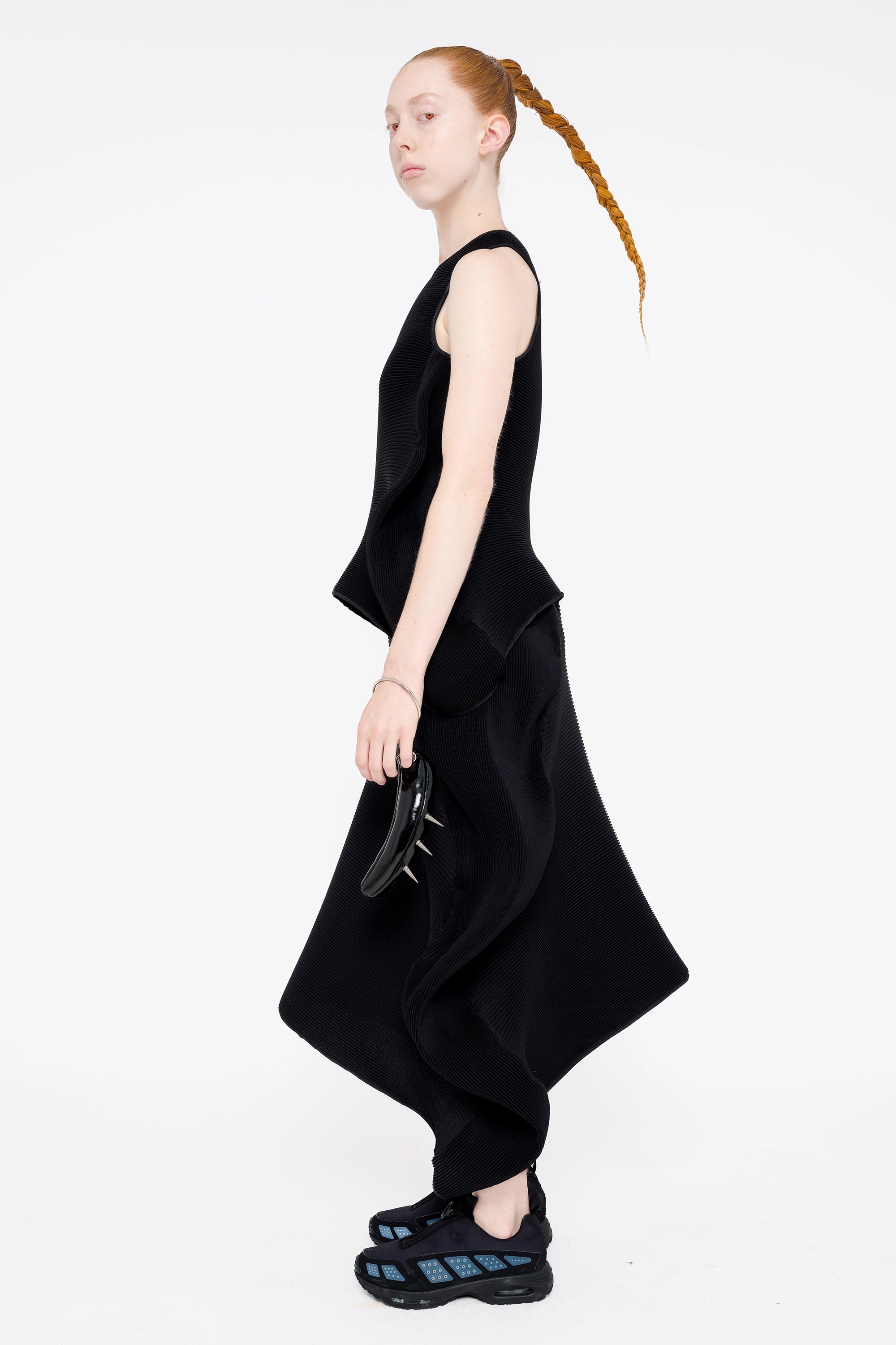 female-wearing-black-pleated-top-with-ruffles-and-black-long-pleated-skirt-with-ruffles-on-white-background-full-body-side