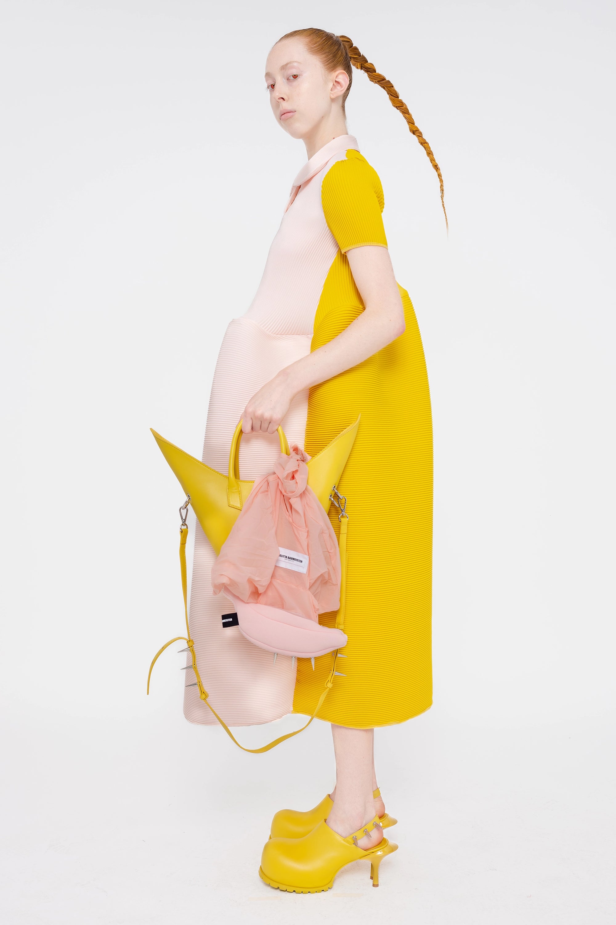 female-wearing-soft-pink-and-yellow-pleated-dress-with-polo-collar-and-ruffled-skirt-on-white-background-full-body-side