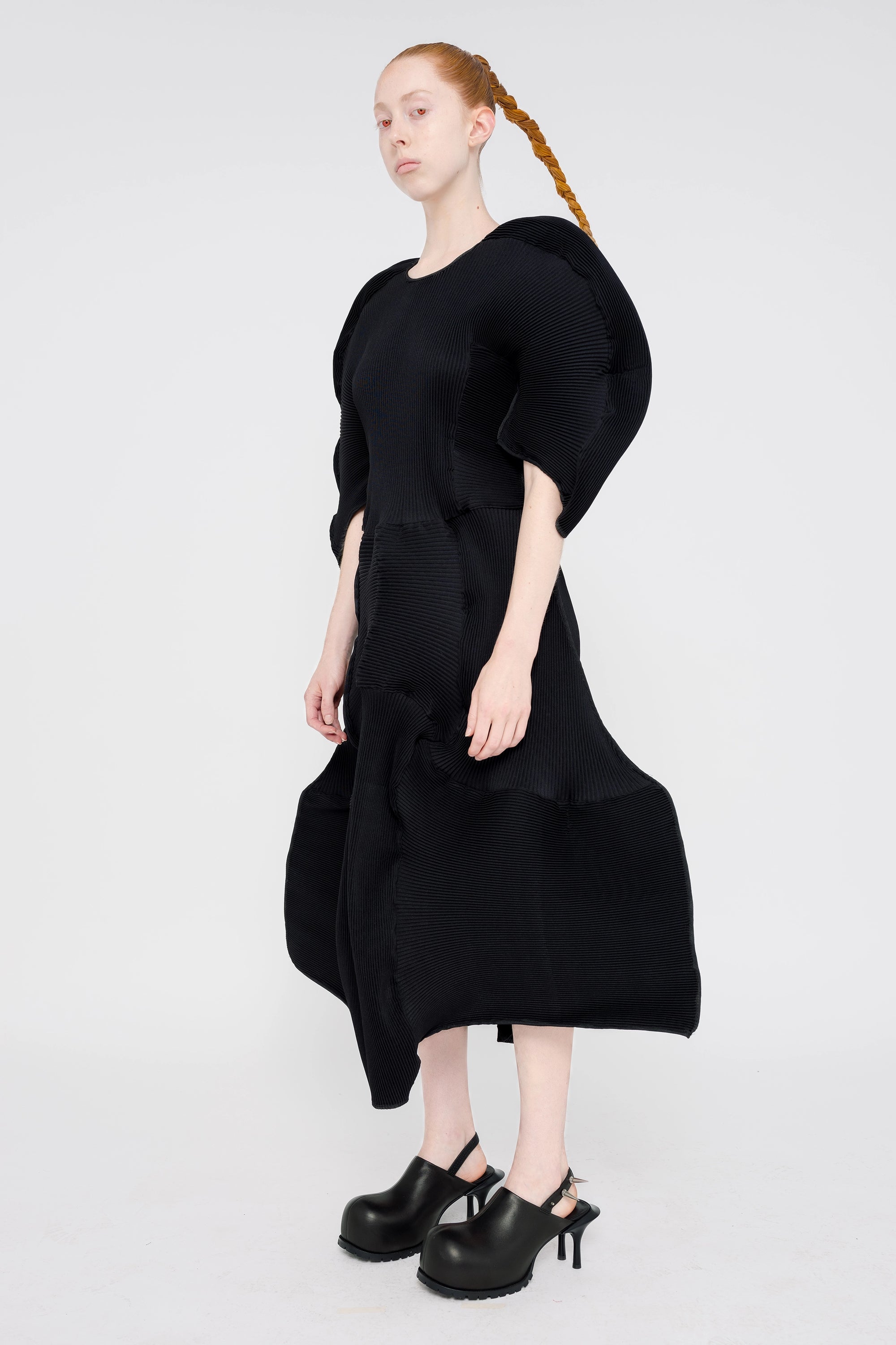 blonde-model-white-background-wearing-big-sleeve-ripple-midi-length-dress-with-black-spikey-double-heeled-mules-full-body-side-red-eyes