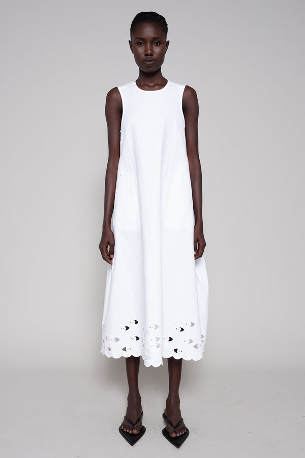 White sleeveless dress with cut-out details on a plain background