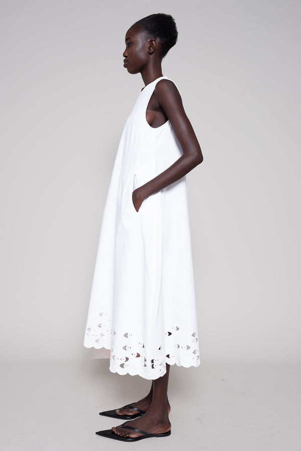 Woman wearing a white dress with cut-out details on a plain background
