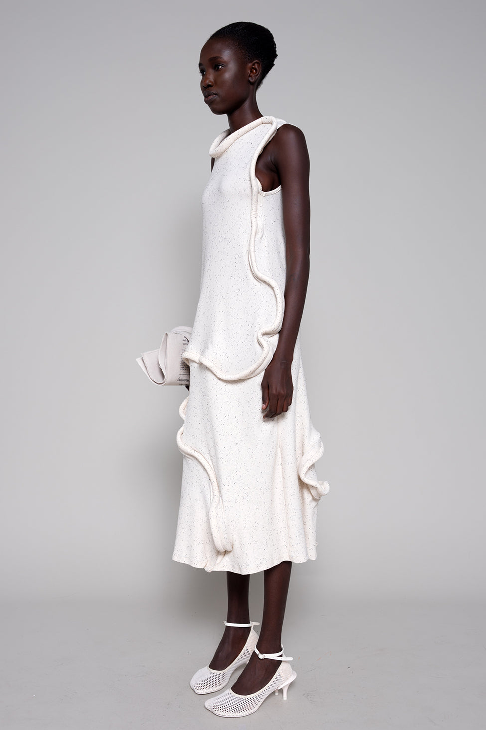 Woman wearing a white dress with ruffled layers on a gray background