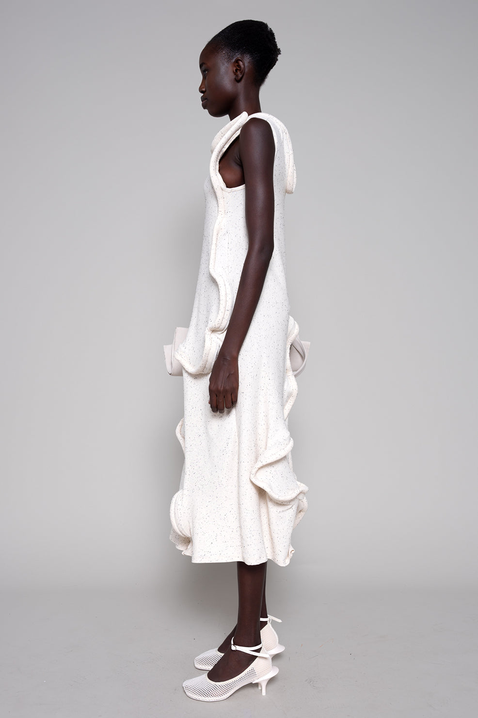 Woman wearing a white dress with ruffled layers on a gray background