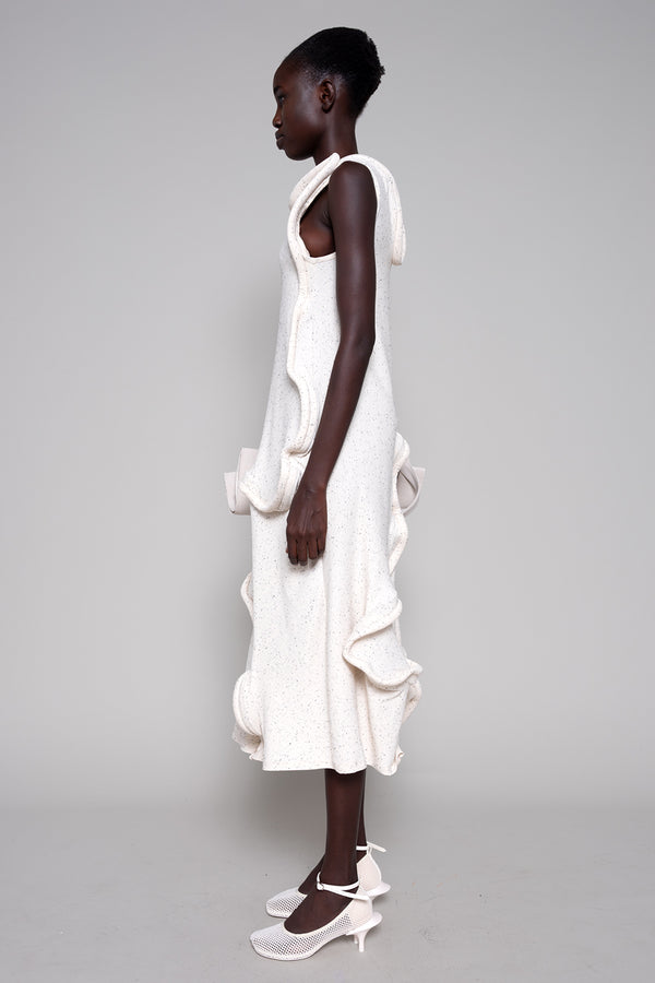 Woman wearing a white dress with ruffled layers on a gray background