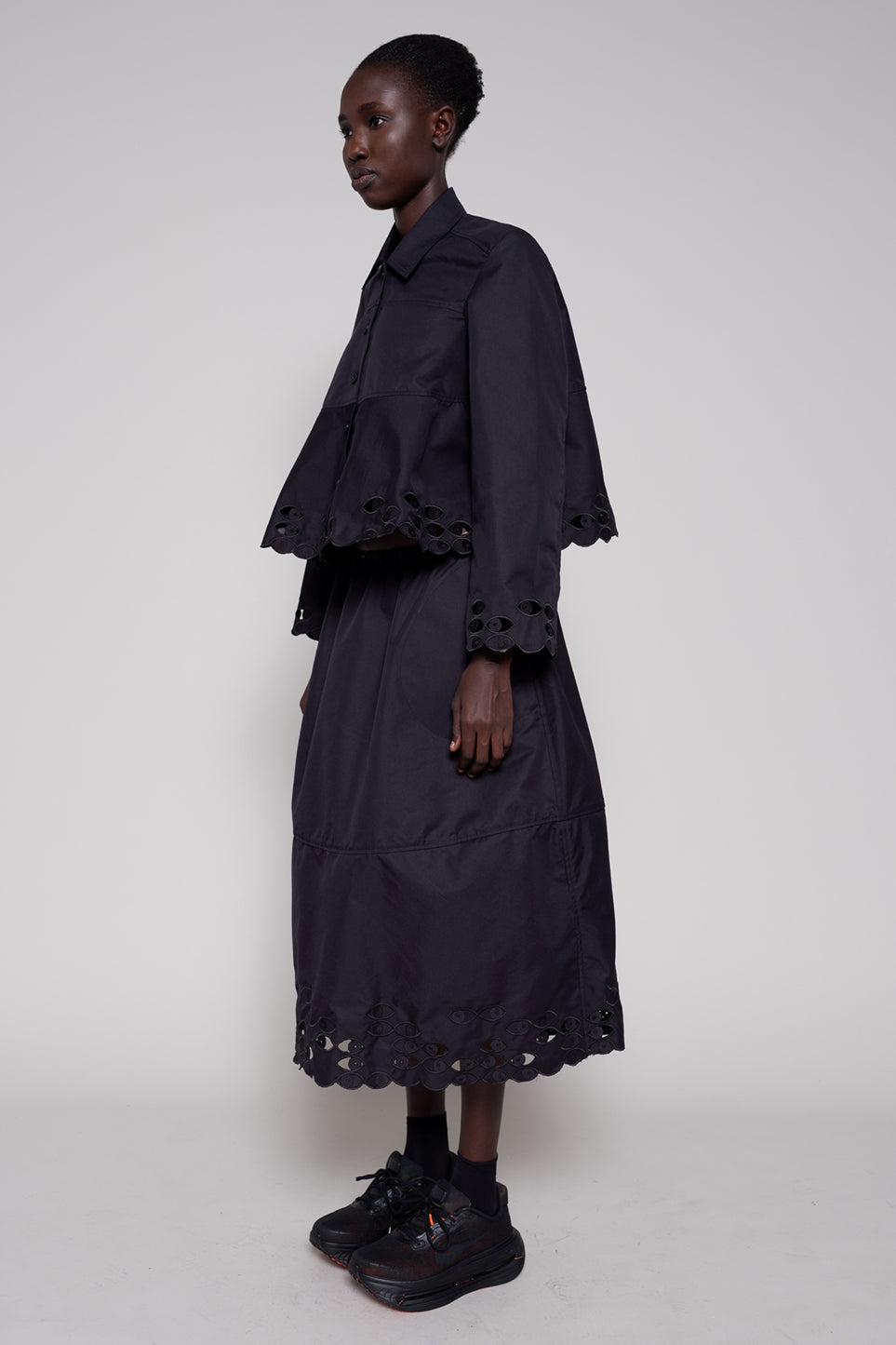 Person wearing a black outfit with ruffled details on a white background