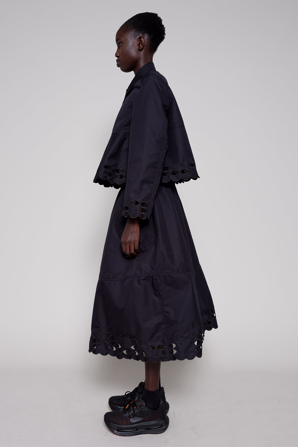 Person wearing a black dress with lace details on a white background