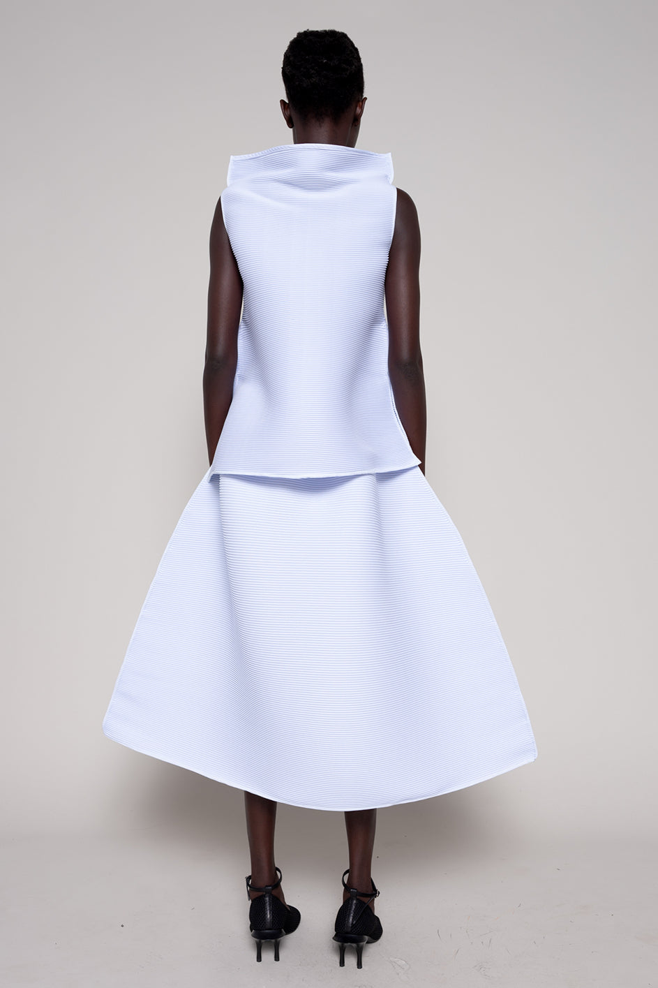 Person wearing a white sleeveless dress against a plain background