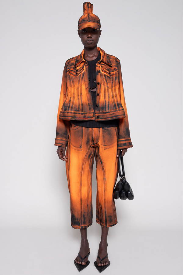 Model front full wearing an orange denim set that's hand-painted black at the seams for a shadow 3-D effect.