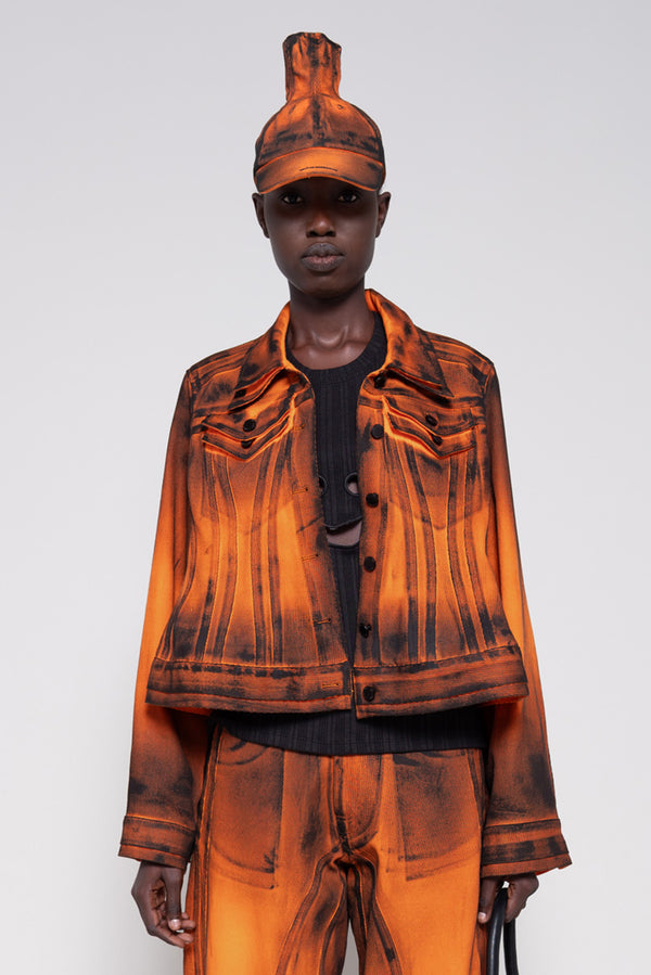 Model wearing an orange denim set that's hand-painted black at the seams for a shadow 3-D effect.