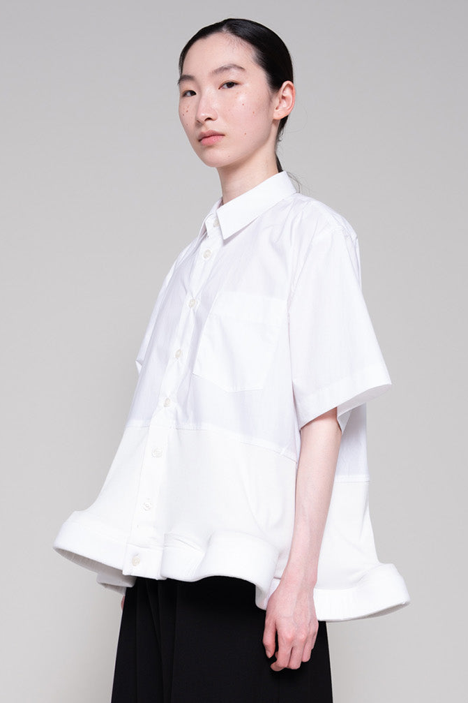 Person wearing a white shirt and black pants on a plain background