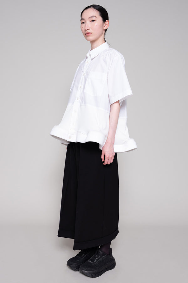 Person wearing a white shirt and black pants on a plain background