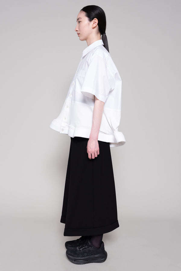 Person wearing a white shirt and black pants on a plain background