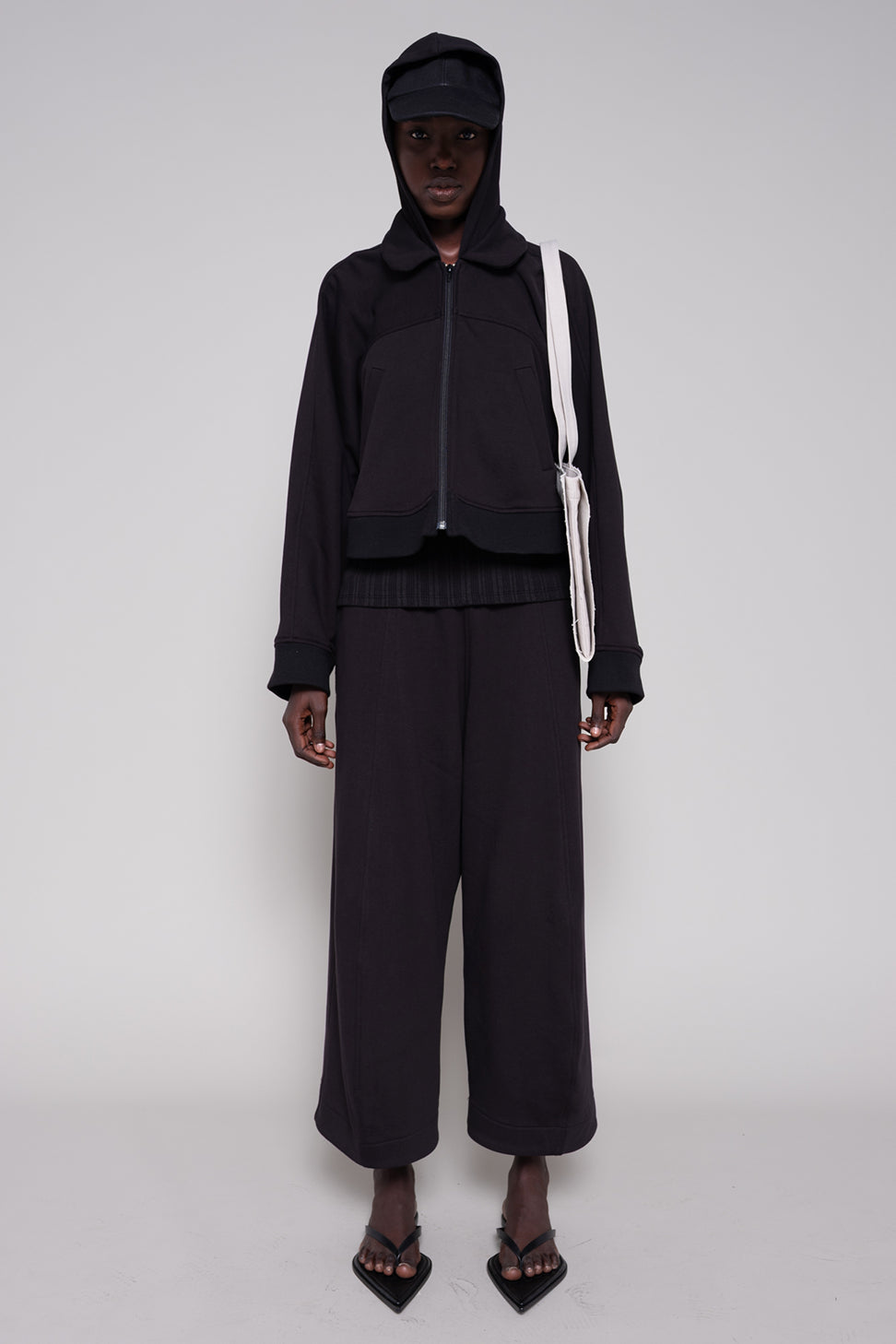 Person wearing a black outfit with a hood on a white background