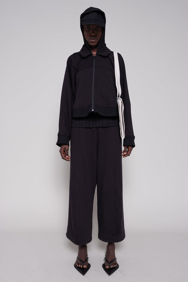 Person wearing a black outfit with a hood on a white background