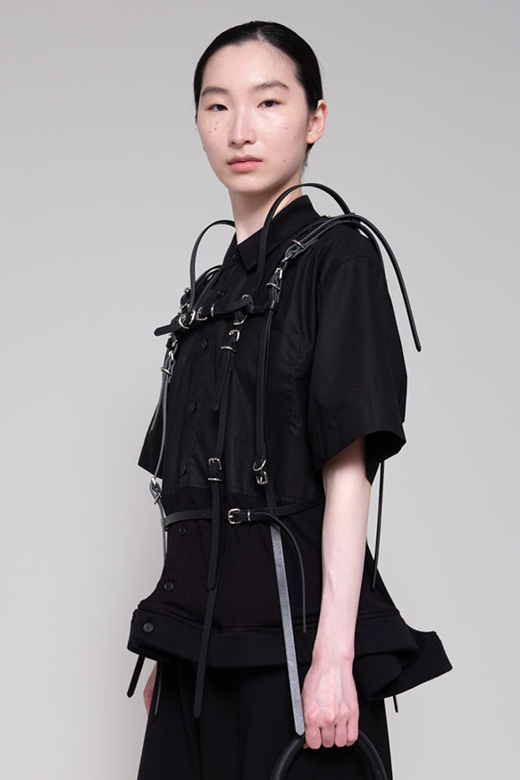 Person wearing a black outfit with straps on a plain background