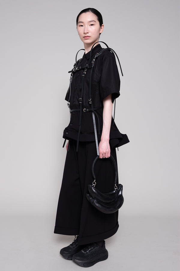 Person wearing a black outfit with a bag on a gray background