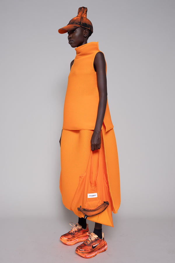 Person wearing an orange outfit with a matching cap on a gray background