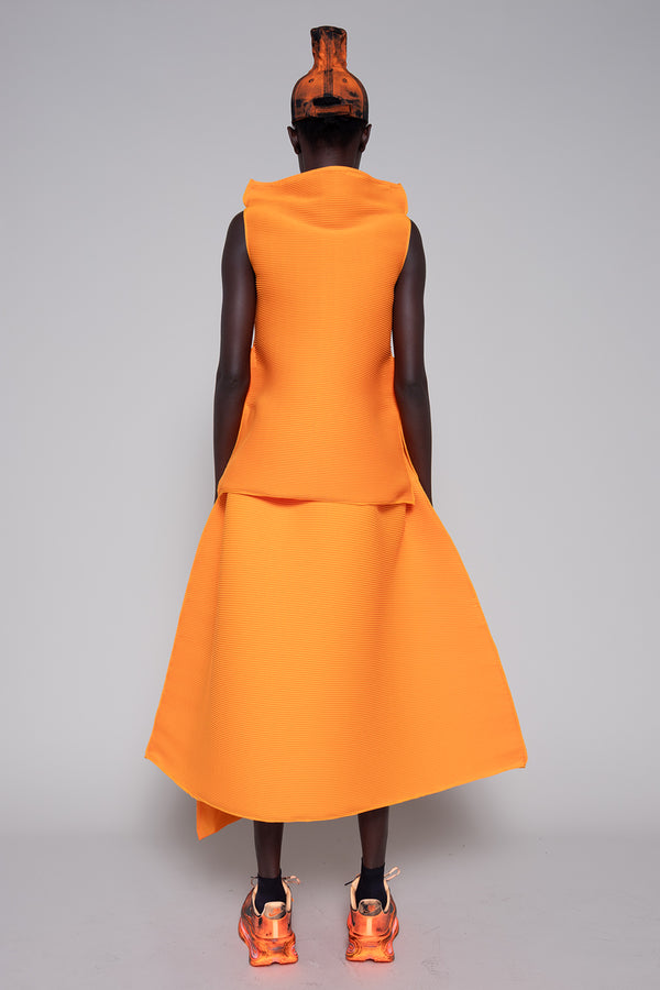 Person wearing an orange sleeveless dress with a hood on a gray background