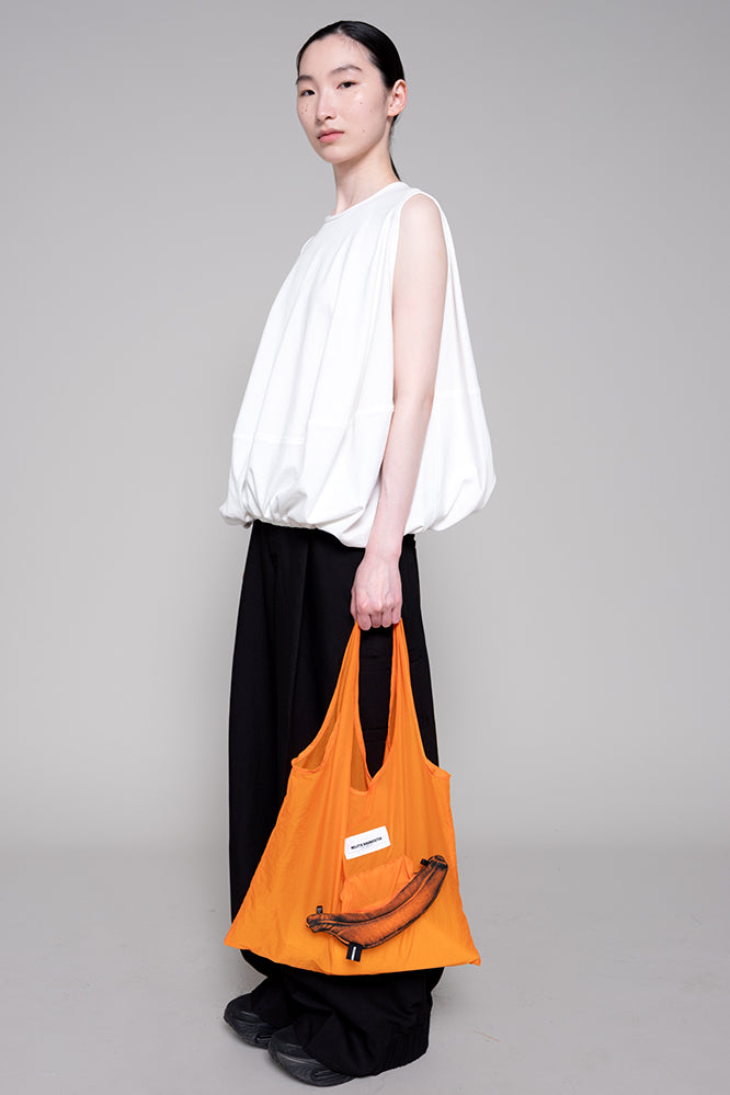 Person holding an orange bag against a gray background