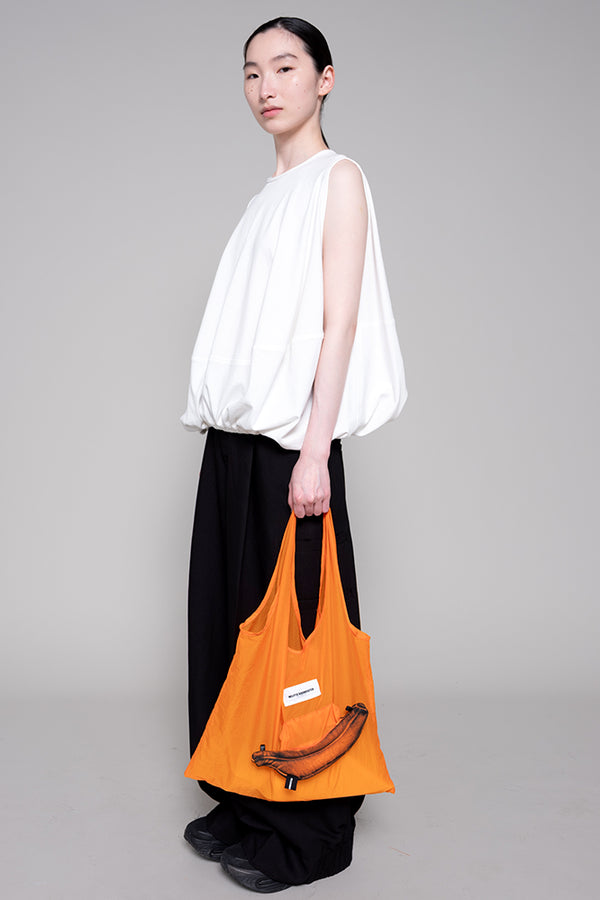 Person holding an orange bag against a gray background