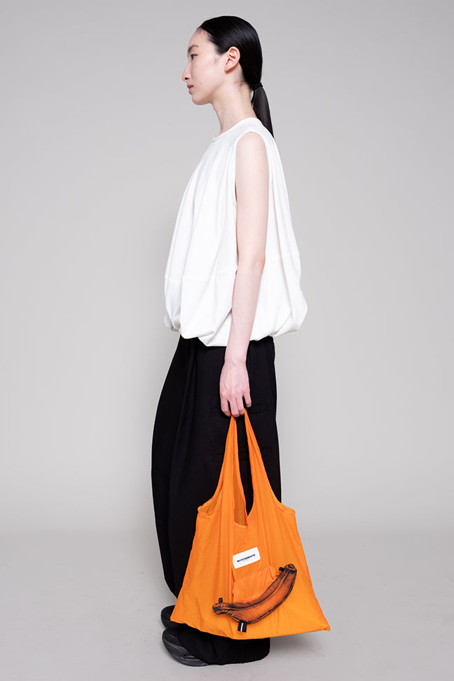 Person holding an orange bag against a plain background