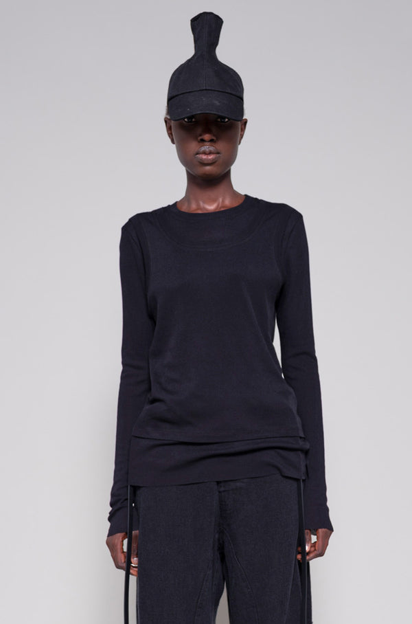 Person wearing a black long sleeve and pants with a hat on a plain background