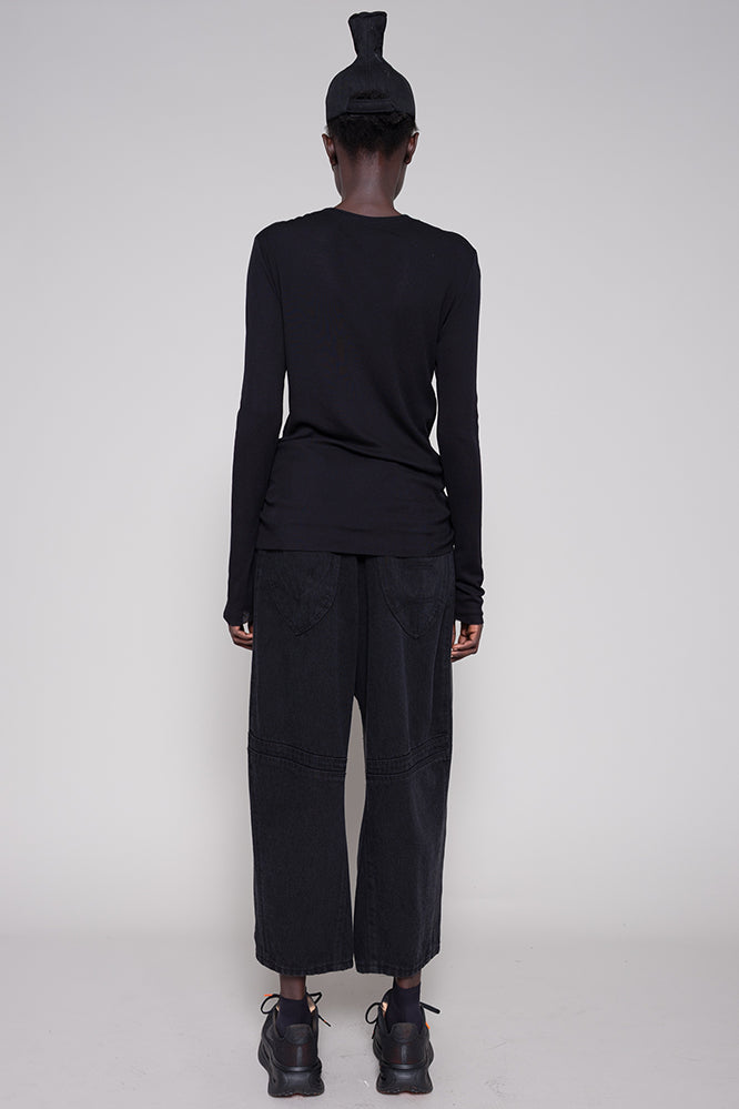 Person wearing a black outfit with wide-leg pants on a white background