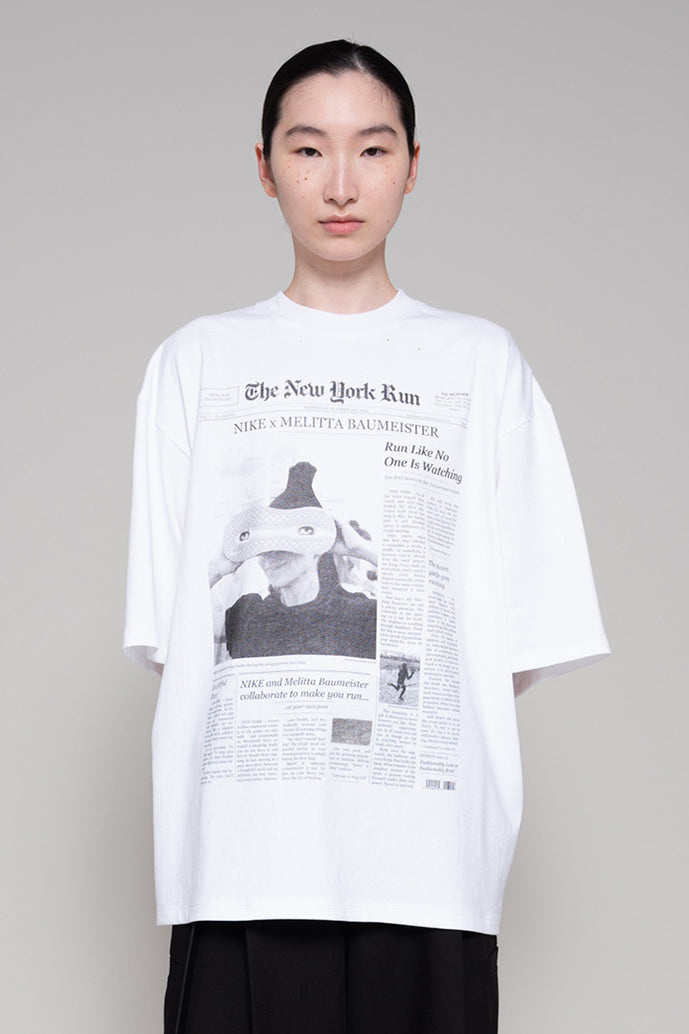 Person wearing a white t-shirt with a printed design on a plain background