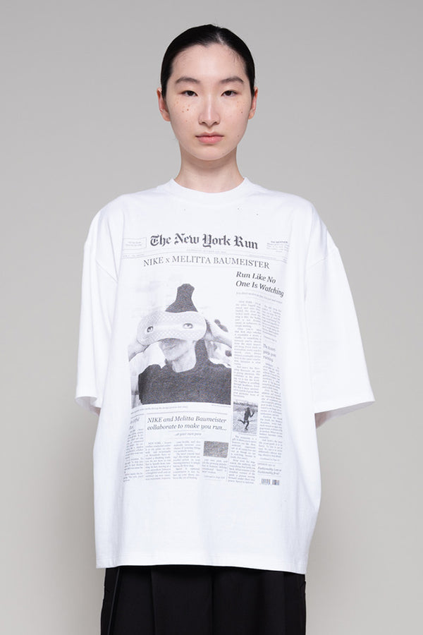 Person wearing a white t-shirt with a printed design on a plain background