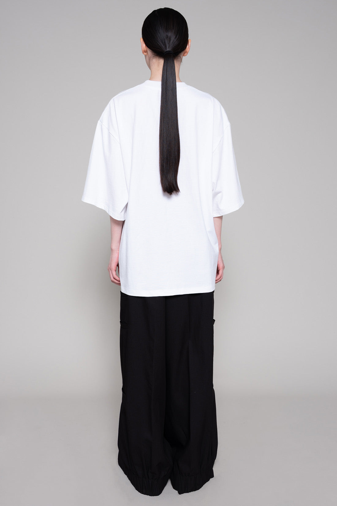 Person wearing a white top and black pants on a gray background