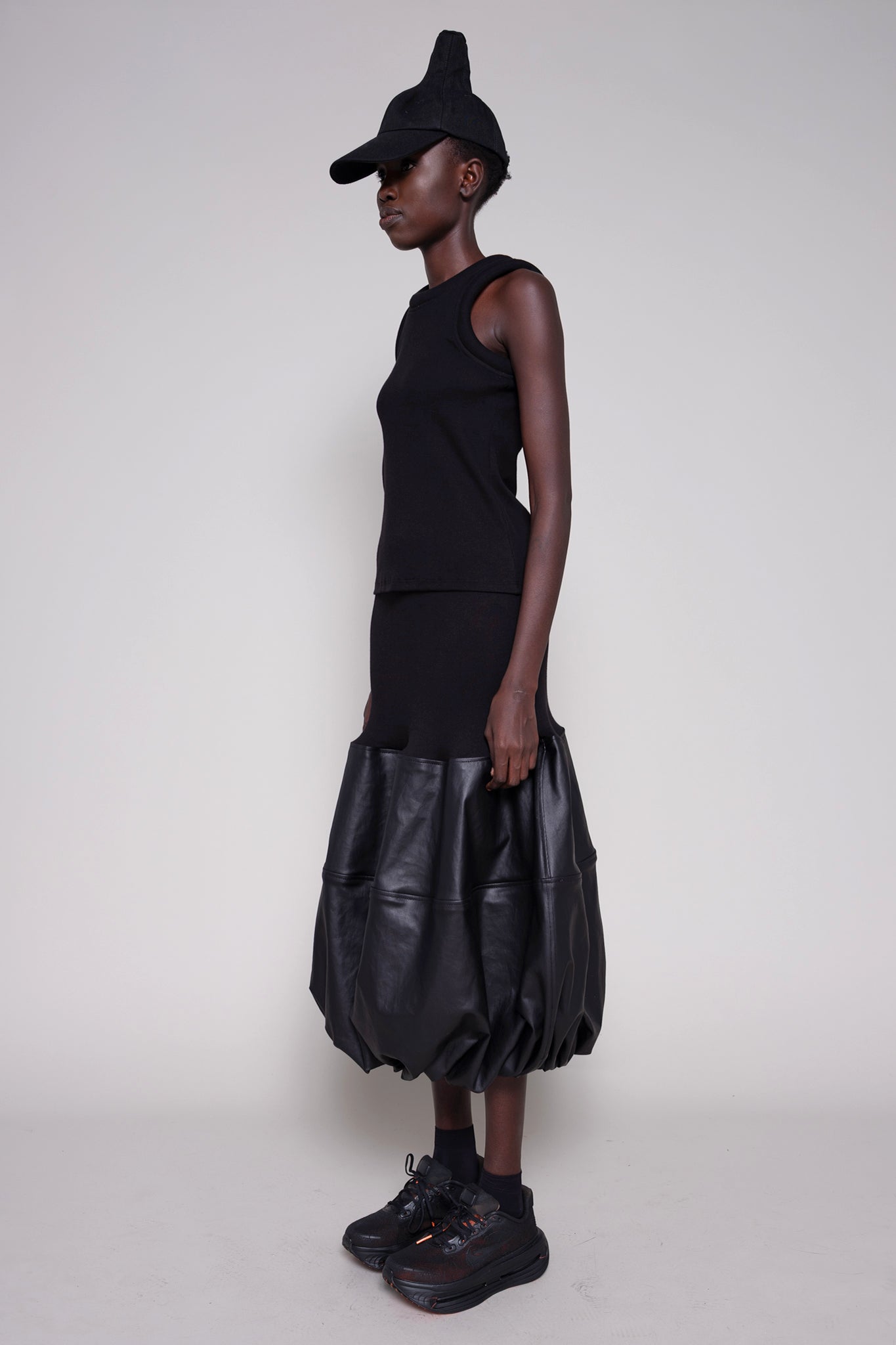 Person wearing a black outfit with a leather skirt on a white background